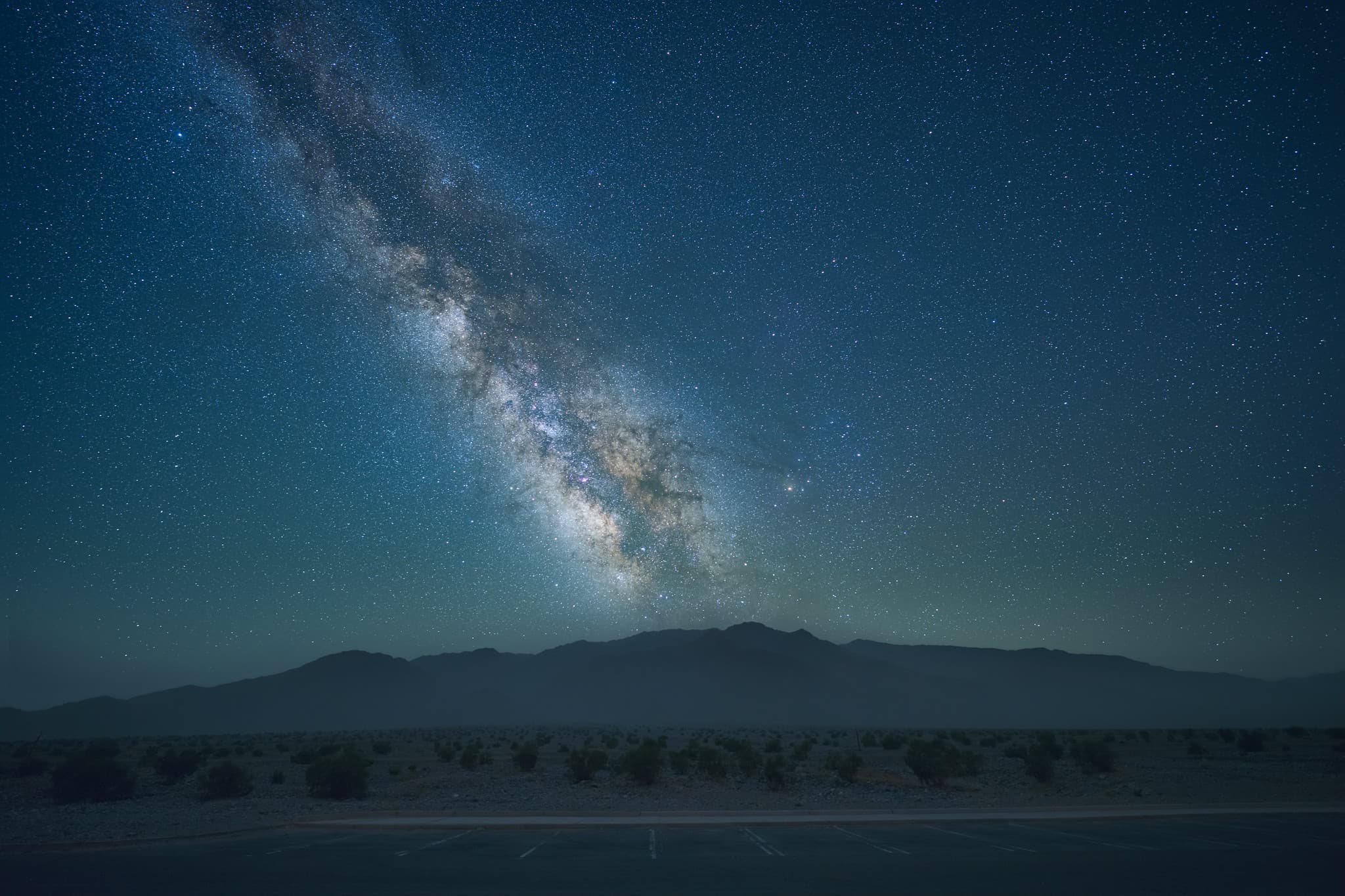 The Milky Way above a dark desert landscape.