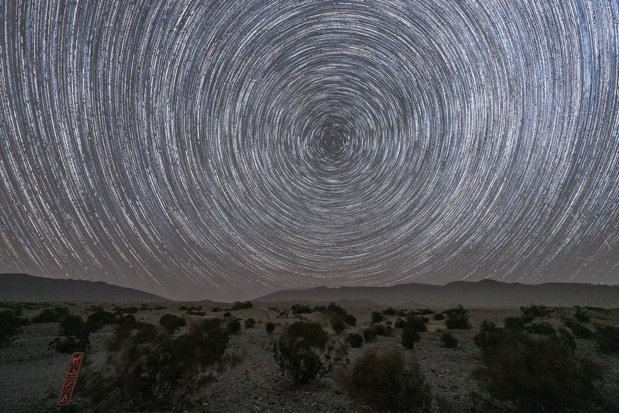 Circular star trails above a desert landscape.